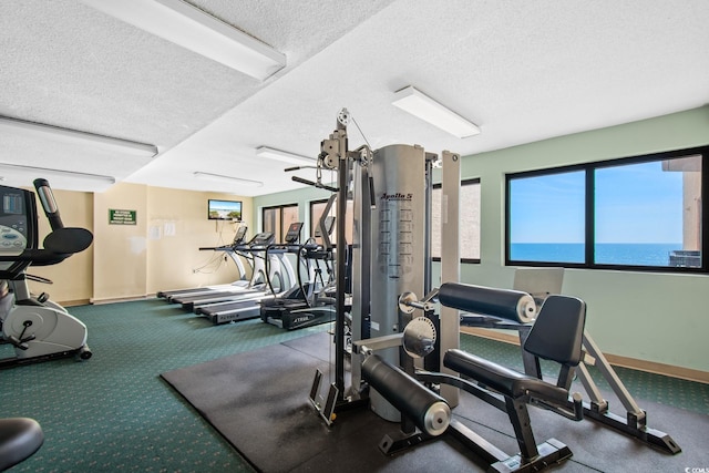 gym featuring a textured ceiling and baseboards