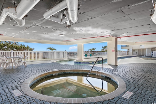 community pool with a community hot tub, fence, and a patio area
