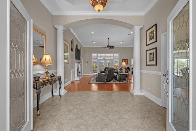 entrance foyer with ornate columns, ceiling fan, arched walkways, light tile patterned floors, and crown molding
