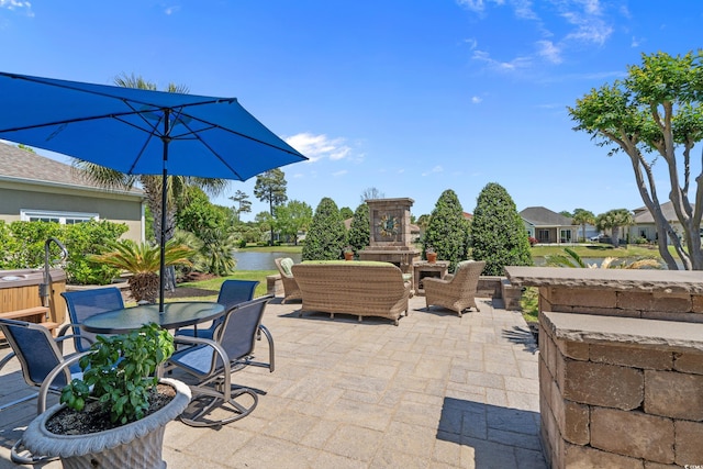 view of patio with outdoor dining space, a hot tub, and a water view