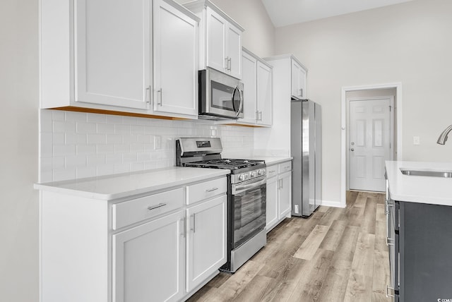 383 Hayloft Cir, Conway, SC 29526 - kitchen featuring appliances with stainless steel finishes, a sink, decorative backsplash, light wood-style floors, and white cabinets