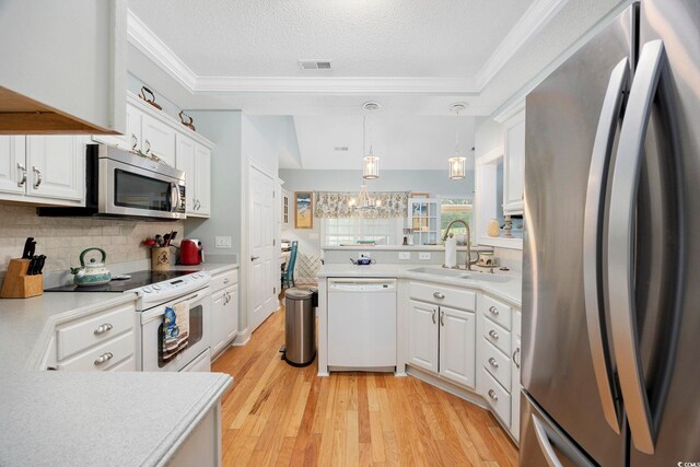 180 Waterhall Dr, Murrells Inlet, SC 29576 - kitchen with appliances with stainless steel finishes, a sink, ornamental molding, white cabinetry, and light wood-style flooring
