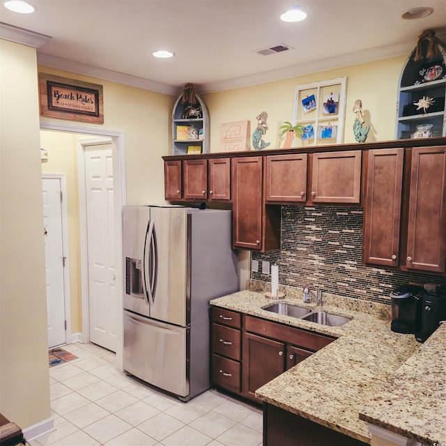 kitchen featuring stainless steel refrigerator with ice dispenser, light tile patterned flooring, backsplash, a sink, and light stone countertops