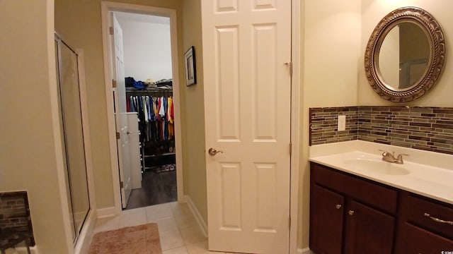 bathroom with a stall shower, tile patterned floors, vanity, baseboards, and a walk in closet