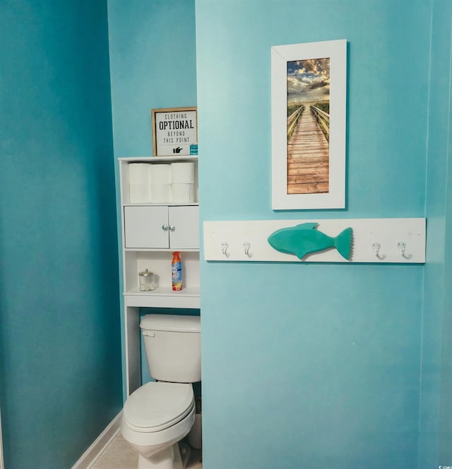 bathroom with toilet, baseboards, and tile patterned flooring
