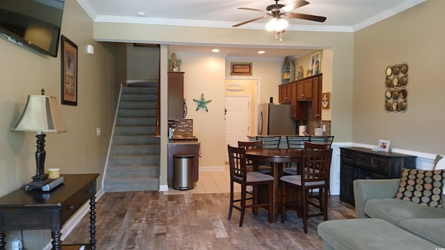 dining room featuring ceiling fan, stairs, wood finished floors, baseboards, and ornamental molding