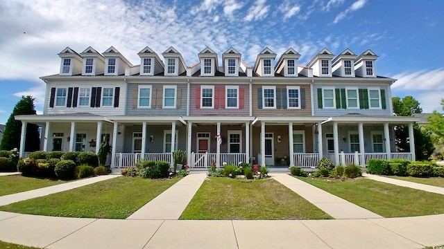 view of property featuring covered porch and a front lawn