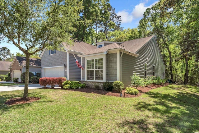 view of front of house with an attached garage, concrete driveway, a front lawn, and a shingled roof