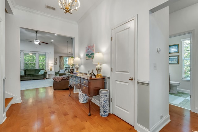 hallway featuring light wood-style floors, healthy amount of natural light, crown molding, a chandelier, and baseboards