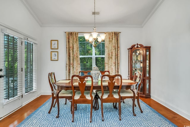 dining room with a chandelier, plenty of natural light, crown molding, wood finished floors, and baseboards