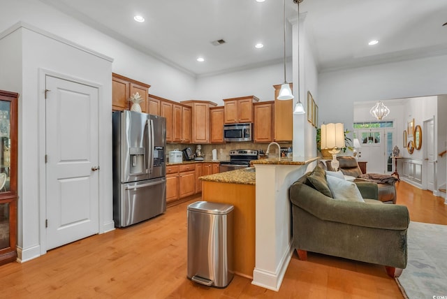 kitchen with stainless steel appliances, a peninsula, brown cabinetry, stone countertops, and decorative backsplash