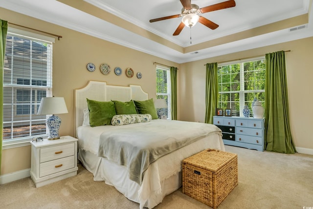 bedroom featuring light carpet, ornamental molding, baseboards, a raised ceiling, and ceiling fan