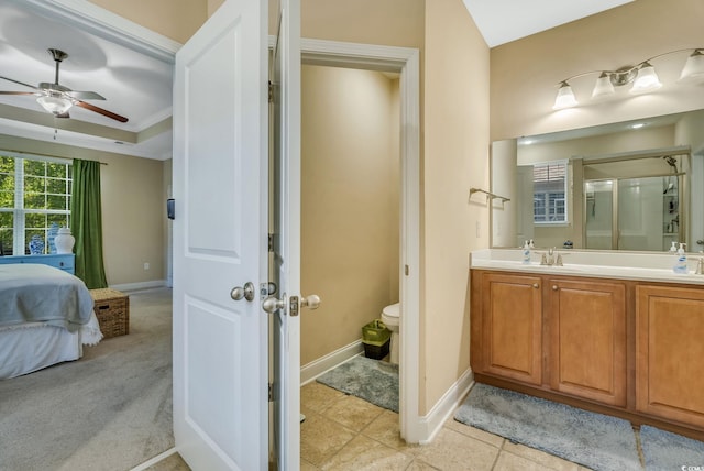 ensuite bathroom with a ceiling fan, a shower stall, vanity, baseboards, and toilet