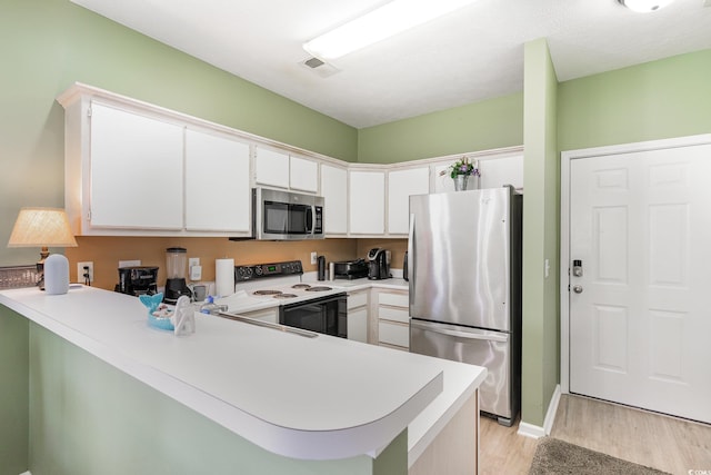 kitchen featuring appliances with stainless steel finishes, light wood-style floors, a peninsula, light countertops, and white cabinetry