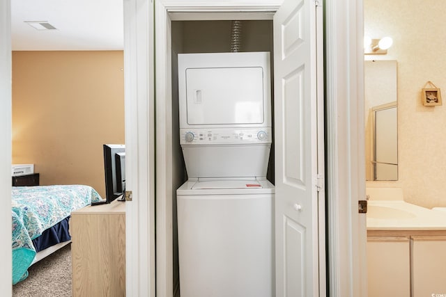 laundry area featuring stacked washer and clothes dryer and carpet floors