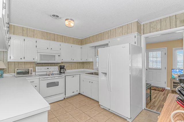 kitchen featuring white appliances, ornamental molding, a textured ceiling, light countertops, and light tile patterned floors