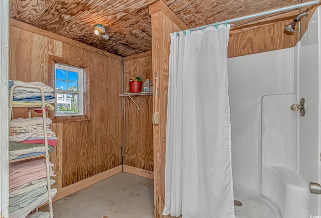 bathroom with a shower with curtain, concrete flooring, and wood walls