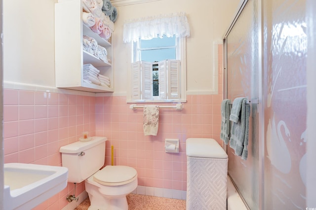215 28th Ave S, Myrtle Beach, SC 29577 - bathroom with tile walls, toilet, a wainscoted wall, and a sink