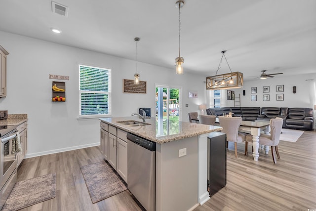 kitchen featuring appliances with stainless steel finishes, a sink, light wood-type flooring, light stone countertops, and a ceiling fan