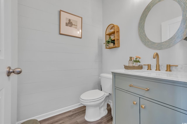 bathroom featuring wood finished floors, toilet, vanity, and baseboards