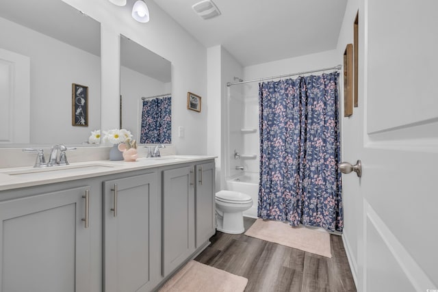 bathroom featuring wood finished floors, double vanity, toilet, and shower / bath combination with curtain