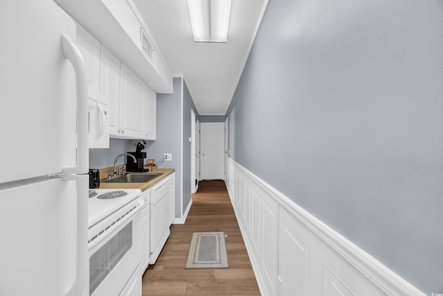 9400 Shore Dr Unit 206, Myrtle Beach, SC 29572 - kitchen featuring white appliances, a sink, white cabinets, light wood-style flooring, and a wainscoted wall