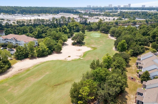 drone / aerial view of a golf course and a tree filled landscape