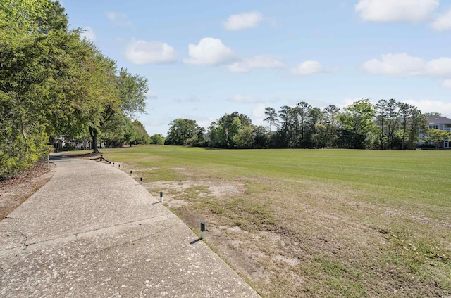 surrounding community with a yard, view of wooded area, and golf course view