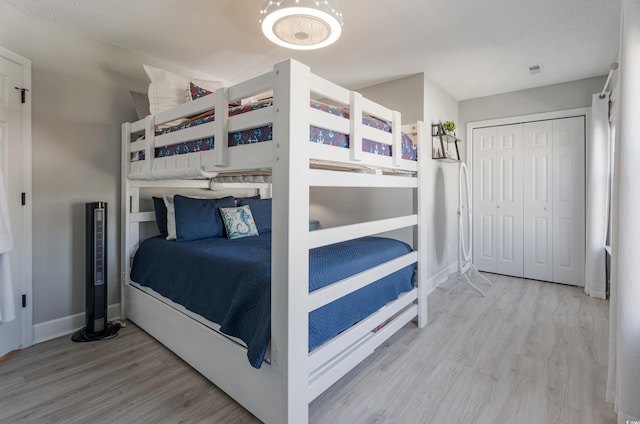 bedroom featuring wood finished floors, baseboards, and a closet