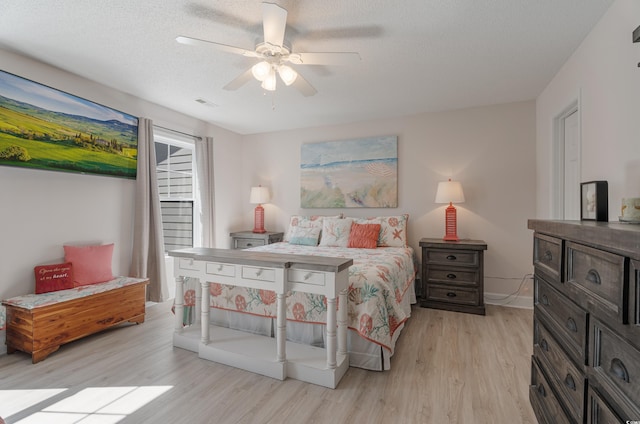 bedroom with light wood finished floors, ceiling fan, and a textured ceiling
