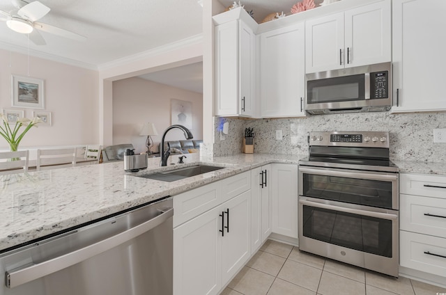 kitchen featuring stainless steel appliances, a sink, crown molding, light tile patterned flooring, and a ceiling fan