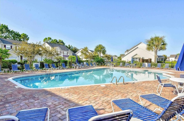 community pool with a patio area, fence, and a residential view