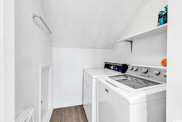 washroom featuring a textured ceiling, washing machine and clothes dryer, wood finished floors, and baseboards