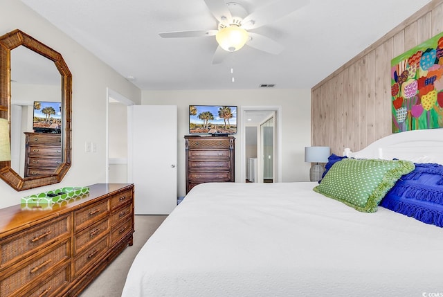 carpeted bedroom with wood walls and a ceiling fan