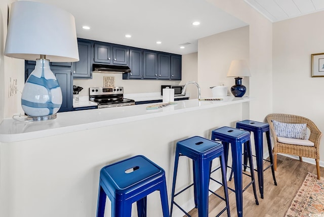 kitchen featuring stainless steel electric range oven, a peninsula, light wood-style floors, light countertops, and recessed lighting