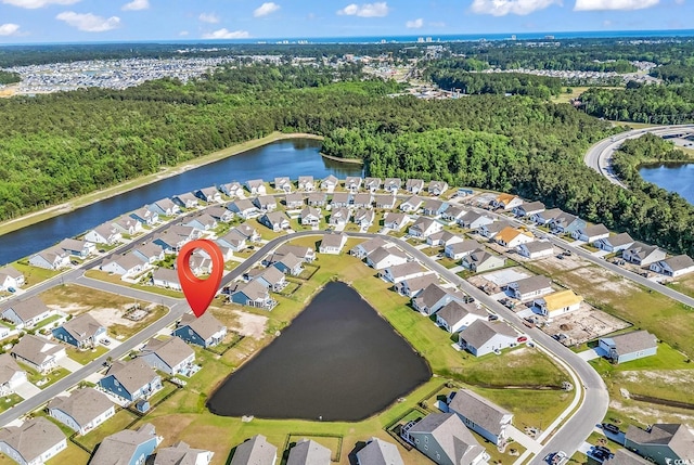 aerial view of property and surrounding area with a large body of water, a forest, and nearby suburban area
