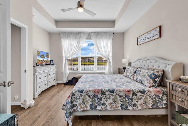 bedroom with light wood-style floors, a ceiling fan, and baseboards