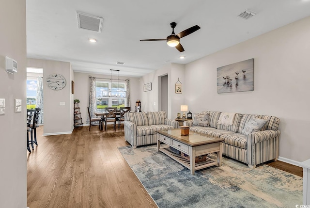 living area featuring wood finished floors, ceiling fan, a chandelier, baseboards, and recessed lighting
