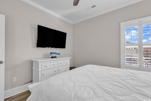 bedroom featuring crown molding, baseboards, wood finished floors, and a ceiling fan