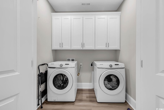 laundry room featuring independent washer and dryer, cabinet space, light wood-type flooring, and baseboards