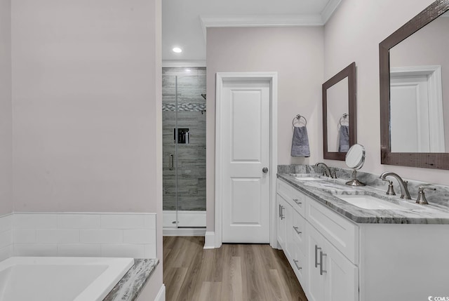 full bath with ornamental molding, a stall shower, wood finished floors, a garden tub, and double vanity
