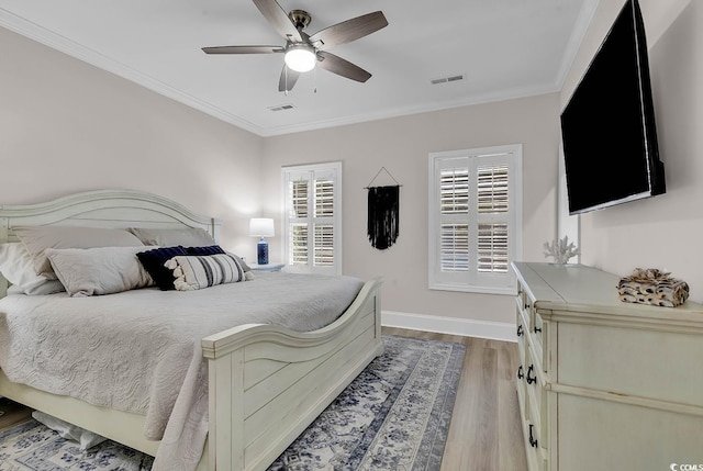 bedroom featuring light wood-style flooring, ornamental molding, baseboards, and a ceiling fan