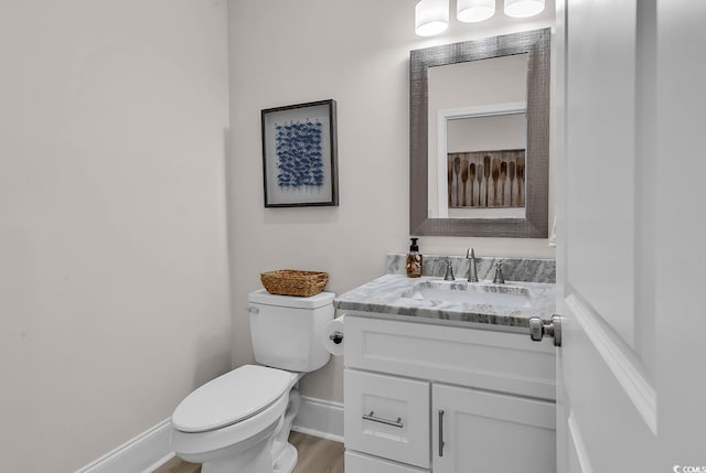 bathroom featuring toilet, vanity, baseboards, and wood finished floors