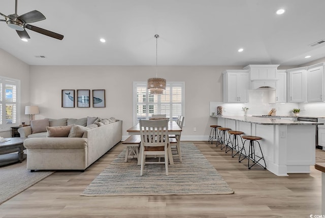 living area with healthy amount of natural light, light wood-type flooring, a ceiling fan, recessed lighting, and baseboards