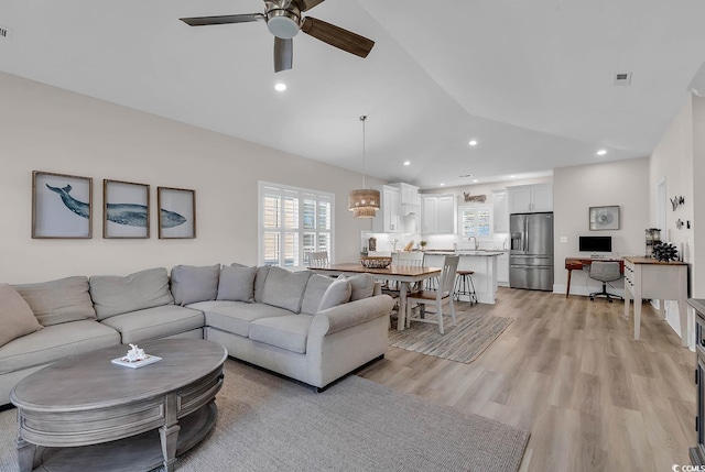living room featuring lofted ceiling, a ceiling fan, light wood-style floors, and recessed lighting