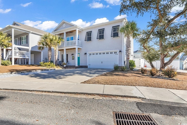 view of front of property with an attached garage, driveway, a balcony, a ceiling fan, and fence