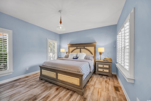 bedroom with light wood finished floors, baseboards, and multiple windows