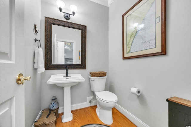 half bathroom with wood finished floors, toilet, baseboards, and a sink