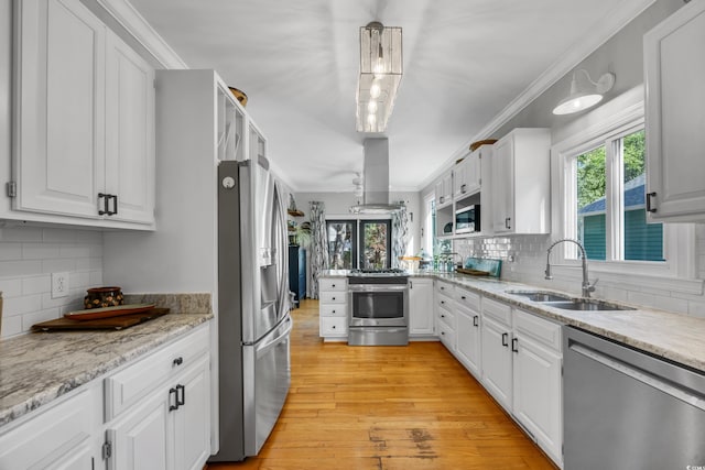 kitchen featuring appliances with stainless steel finishes, a sink, island exhaust hood, tasteful backsplash, and ornamental molding