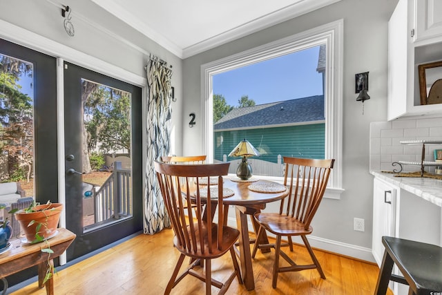 dining room featuring light wood-style flooring, ornamental molding, and baseboards